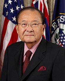 Head and shoulders portrait of an older Asian man wearing a business suit and tie.