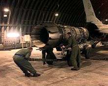 View of a jet engine being pushed up to the empty rear of an F-16