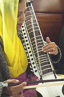 Woman in yellow scarf bowing an instrument
