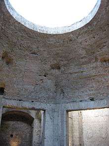 Bare concrete octagonal dome interior at Nero's palace showing flat sections springing from above square doorways and merging into a spherical shape that culminates in a large circular oculus at the top