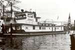 alt=Black-and-white photo of long towboat on the water