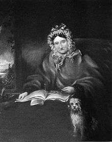 Half-length portrait of a woman wearing a frilly cap. She is in bed, with a book, her glasses, and her dog.