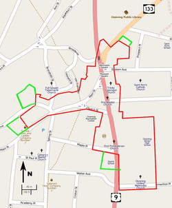 A map of the streets in downtown Ossining, on a gray background with major roads in pink and orange and the locations of some landmarks indicated. The border of the irregularly-shaped historic district is in red. Four small green-bordered areas are adjacent to it.