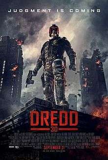 A futuristic police officer in armour and a helmet that covers all but his mouth stands on the corner of a building roof with a gun in his hand as large tower blocks burn behind him. Above the man reads a tagline "Judgment is Coming".