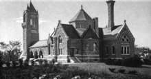 Engraving of a Romanesque building with a gabled roof, a square bell tower and a tall chimney