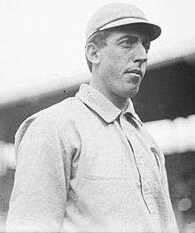 A black-and-white photo of a Caucasian man in a white uniform with a collar turned down.