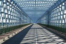 A two-lane road caged in intertwined steal bars, in a style reminiscent of the Eiffel tower.