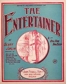 The front cover of The Entertainer sheet music. It has a green background and in the centre is a red ink drawing of a stereotyped African-American performer on stage in top hat and tails