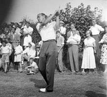 Black-and-white photograph from the front of Eric Brown which shows him finishing his golf swing over his left shoulder.