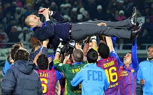 A group of association football players, who played for FC Barcelona at the time of the photo, lifting their coach after winning their second FIFA Club World Cup.