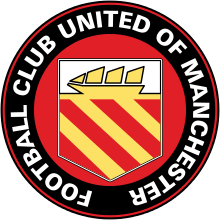 A circular badge with "Football Club United of Manchester" written in white capitals just inside the black circumference with a red trim. Inside is a yellow crest on a red background. The crest has a yellow ship with three sails on a white background, and three yellow stripes on a red background.