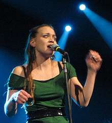 Fiona Apple wearing a green outfit while singing.