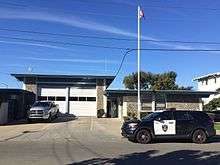 A small fire station with an American flag and police SUV in front