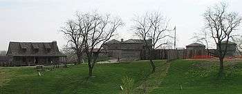 Three trees in foreground on cut grass, farmhouse-style buildings across background
