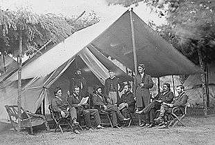 Civil war era photograph of a large tent with a gathering of high-ranking officers, some seated and some standing.