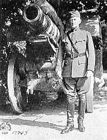 A black and white image showing Edwards in his military uniform standing next to a large cannon.