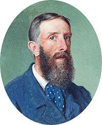 Oval shaped portrait of a bearded man, wearing a blue jacket and a blue, spotted cravat