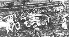 a black and white photograph of troops and animals pulling vehicles out of the mud
