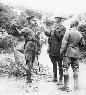 three men dressed in uniform standing on scrubby terrain