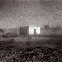 A blurred black-and-white photo of a building in the middle of a desert