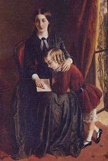 Portrait of a governess, wearing a black dress, seated on a red chair. She is teaching a child with blonde curls and a red velvet dress to read. The child is standing up, leaning into her lap to see the book she is pointing to.
