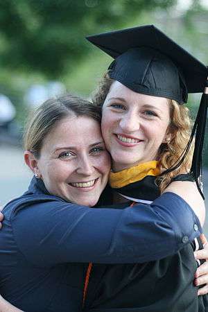 Two people hugging; one with a graduation cap.