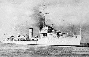 Three-quarter front view of destroyer with twin funnels and two forward gun turrets, at sea