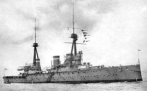A large grey warship with two tripod masts and three funnels