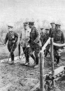 Two British and one French General lading a group of four British officers across a small wooden bridge