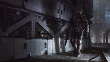 Low angle shot of an industrial area. An armored soldier carrying a weapon looks over his shoulder. Harsh lighting cuts through the gloomy darkness and illuminates the soldier, casting shadows on the wall behind him.