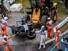Picture of a damaged silver Formula One car being removed from the track