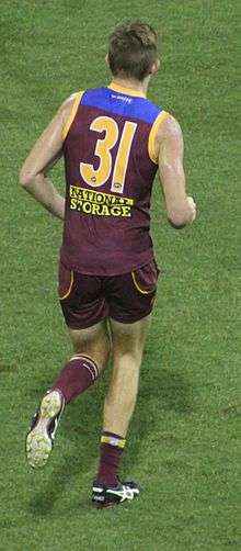 A man in a maroon, blue and gold football jersey wearing number 31 and facing away from the camera runs on grass.