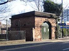 A small sandstone building with a large round-headed arch