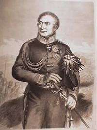Black and white print shows a clean-shaven man holding a sword with a bicorne hat tucked under his left arm. He wears a plain dark military uniform with an Iron Cross and several other decorations.