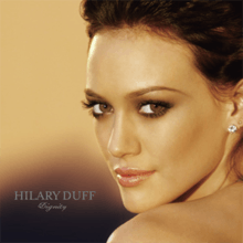 The face and shoulders of a young woman looking over her left shoulder. She has brown hair and wears small crystal earrings. To the left of her image, the words "Hilary Duff" are written in silver, capital letters, with "Dignity" in silver, italic, cursive letters below that.