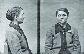 Police mugshots in black and white of middle aged woman sitting on a chair wearing a cardigan and looking listlessly into the camera