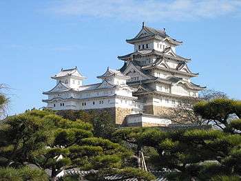 A multistoried white castle donjon with several small towers and a main tower on a platform of stone.