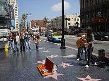 Several stars on the Walk of Fame at 6801 Hollywood Boulevard, with Street performers and passersby