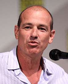 A man in a white shirt stands next to a microphone in a convention.