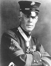 Top half of man in formal 1900s military dress, wearing a star-shaped medal on a ribbon around his neck.