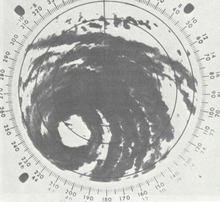 Black and white radar image of a tropical cyclone; gray areas denote areas where rainfall is occurring. Although only a portion of the tropical cyclone is visible, rainbands and a central eye feature can be clearly made out.
