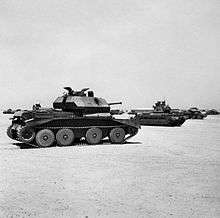 Several tanks parked on sandy-desert surface.
