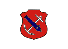 An insiginia in the form of a red shield. On the shield are a white anchor crossed by a blue cannon barrel.