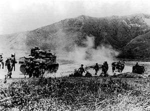 Image of Gurkhas advancing alongside M3 Lee tanks towards foothills in the distance