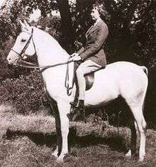 Black and white photograph of Tankersley as a young woman, wearing English riding attire, astride a light gray horse.