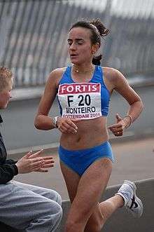 A woman in blue closes her eyes while running through the streets.