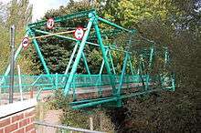 A photograph of a triangle-truss vehicular bridge spanning a river