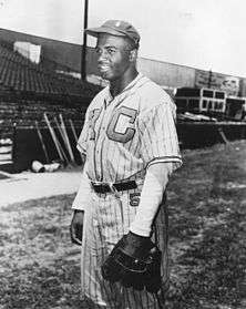 An African-American man wearing a pinstriped baseball uniform, hat, and glove