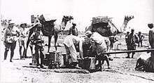 Three soldiers look on while Egyptian workers fill a water fantasie from a pipe