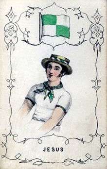 A man wearing a green and white neckerchief and a straw boater, under a green and white flag